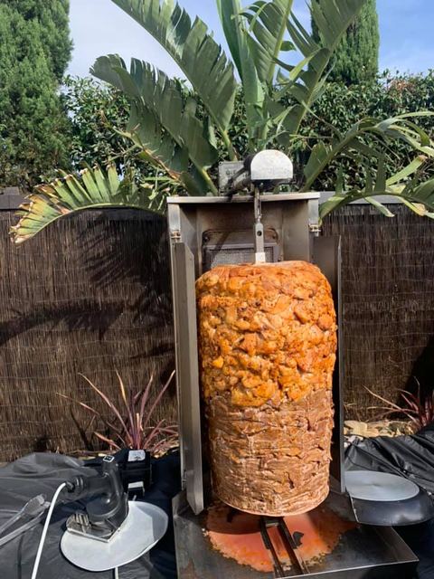 A doner kebab on the spit in an outdoor setup