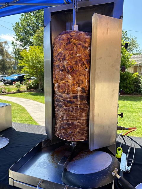 A vertical doner machine set up in a garden