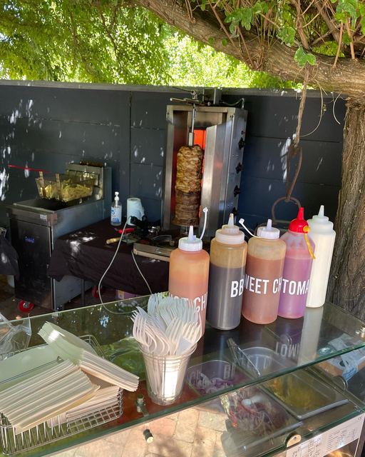 A pop-up kebab station with sauce bottles and the spit behind